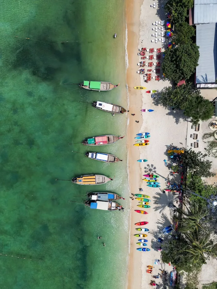 Colourful boats lined up on a white sand beach